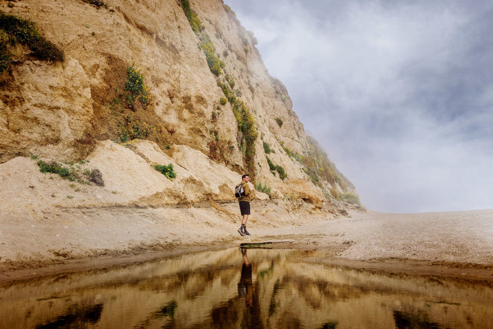 Person walking on beach with cliffs, using Vegas Golden Knights PTX Backpack Cooler