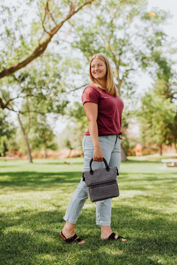 Woman on grass holding a gray lunch bag from Vegas Golden Knights Urban Lunch Bag Cooler